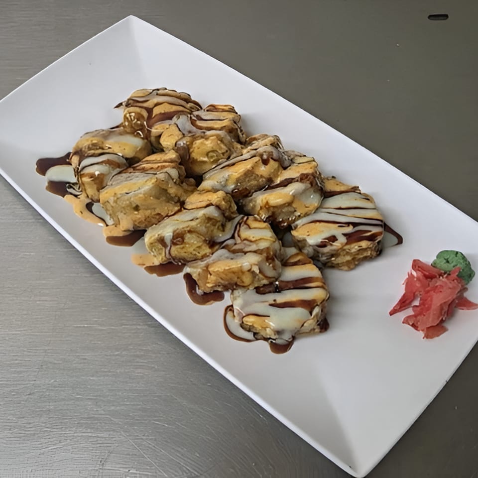 Plate of golden-brown fried oysters drizzled with creamy and dark sauces, garnished with pickled ginger and wasabi.