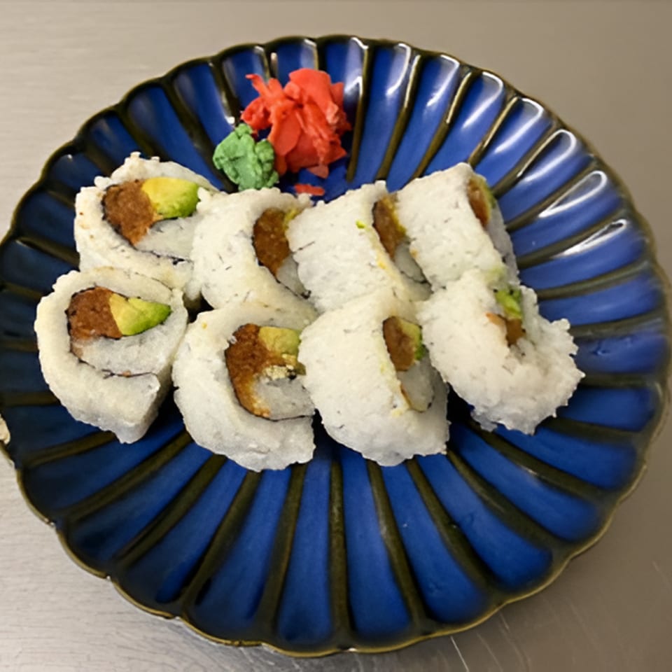 Assorted sushi rolls with avocado and fried filling on a blue plate, garnished with red pickled ginger and green wasabi.