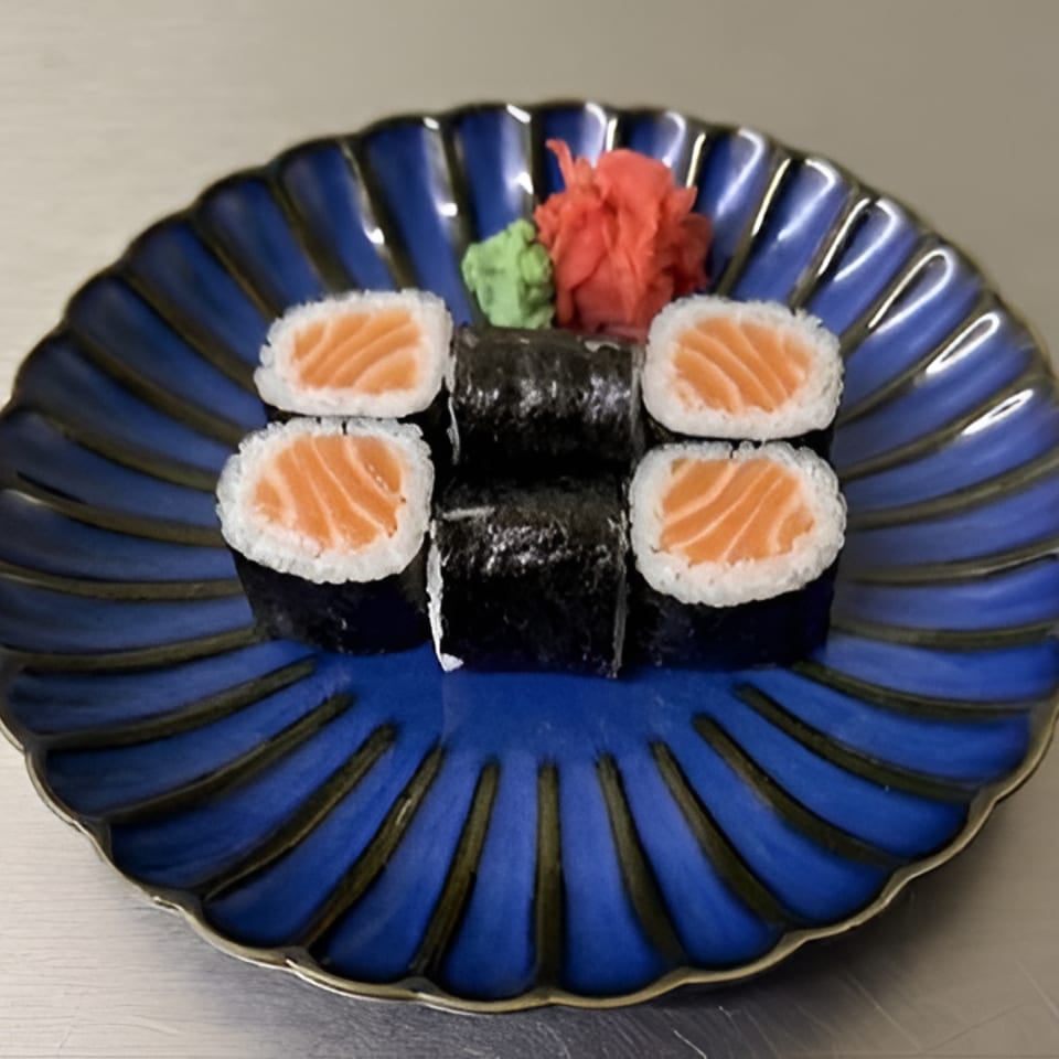 Four salmon sushi rolls and two seaweed-wrapped rolls arranged on a blue decorative plate with wasabi and pickled ginger.